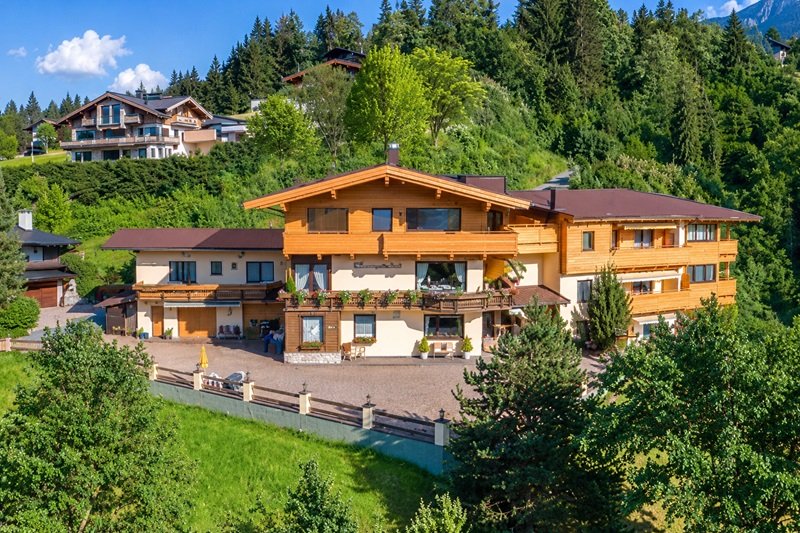 Aparthotel Sonnleitn in St. Johann in Tirol mit Holzfassade, Balkonen und Garten am grünen Hang.